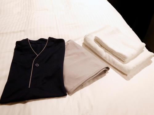 a black suit and white towel on a bed at Gardens Cabin in Sapporo