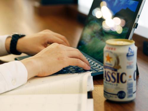 a person typing on a laptop with a cup of coffee at Gardens Cabin in Sapporo