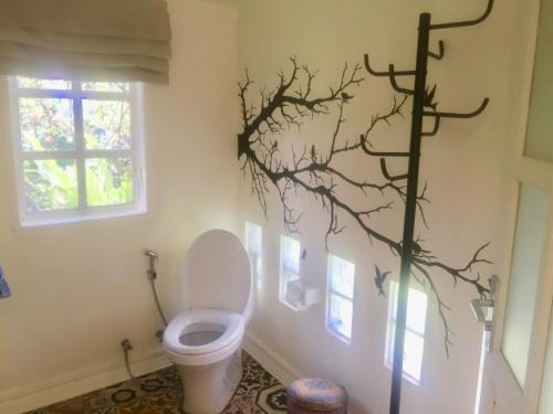 a bathroom with a toilet and a branch on the wall at Pondok Plantation Luxury Mountain Escape Bedugul in Bedugul