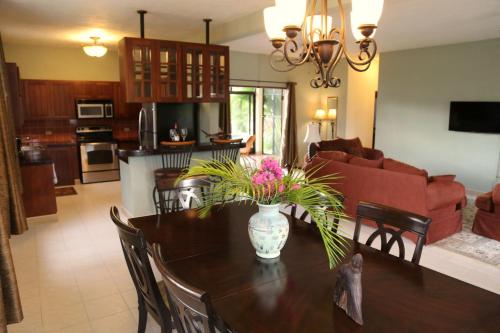 una cocina y una sala de estar con una mesa con flores. en Royale Manor, en Corozal