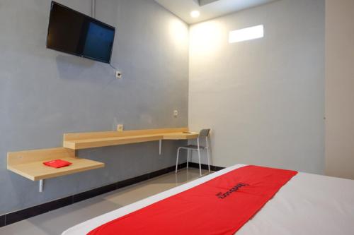 a bedroom with a bed and a desk and a television at RedDoorz Syariah near Alun Alun Tegal in Tegal