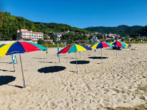 a row of colorful umbrellas on a sandy beach at Izu Kansya in Atami