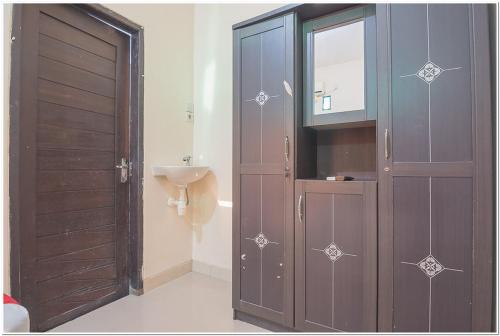 a bathroom with a wooden door and a sink at RedDoorz near Lapangan Tenis Balikpapan in Balikpapan