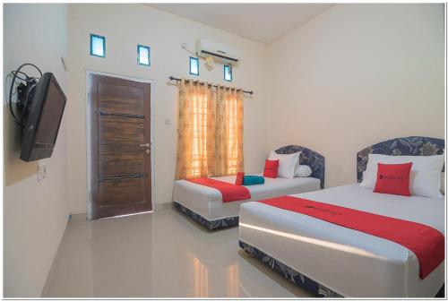 a bedroom with two beds and a tv and a television at RedDoorz near Lapangan Tenis Balikpapan in Balikpapan