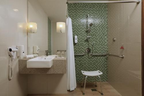 a bathroom with a sink and a shower and a chair at Diamond Hotel Kuta Bali in Kuta