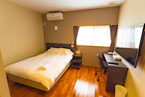a bedroom with a bed and a desk with a computer at Beach Resort Hotel Kalakaua in Onna
