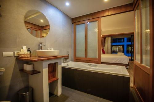 a bathroom with a tub and a sink and a mirror at SugarCane Chiang Mai in Chiang Mai