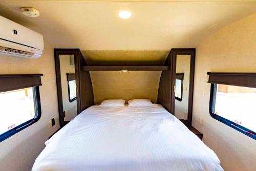 a large bed in a trailer with two windows at Beach Resort Hotel Kalakaua in Onna