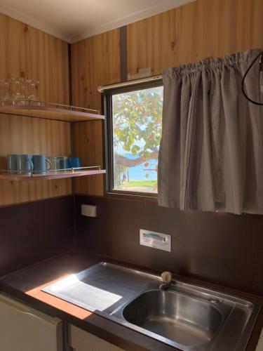 een keuken met een wastafel en een raam bij Horseshoe Bay Resort in Bowen