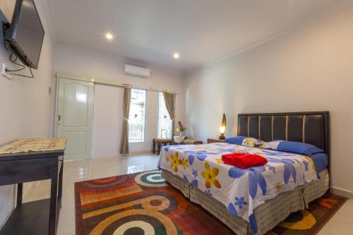 a bedroom with a bed and a desk and a television at Bali Aman Darling House in Canggu