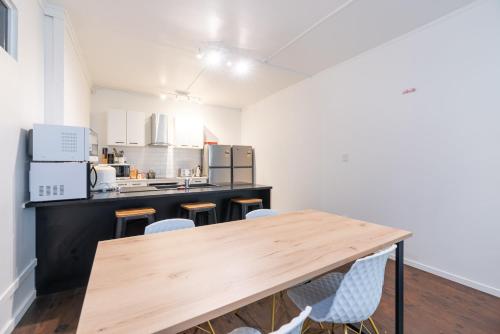uma cozinha com uma mesa de madeira e cadeiras em HIT Hostel em Auckland