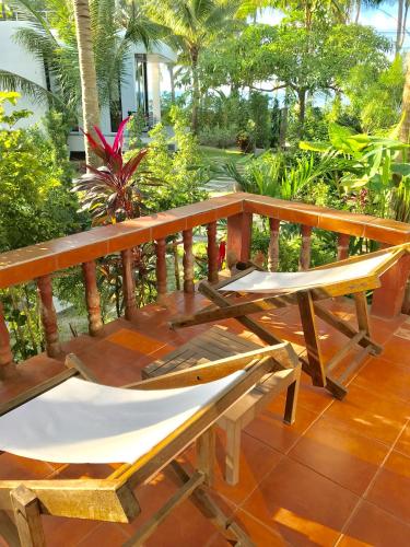 a wooden bench sitting on a deck with trees at Mali House in Mae Nam