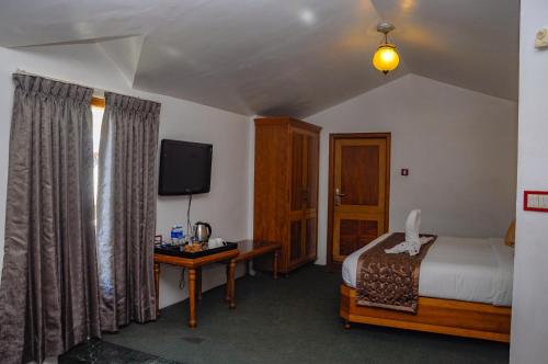 a hotel room with a bed and a television at La Montana by TGI in Ooty