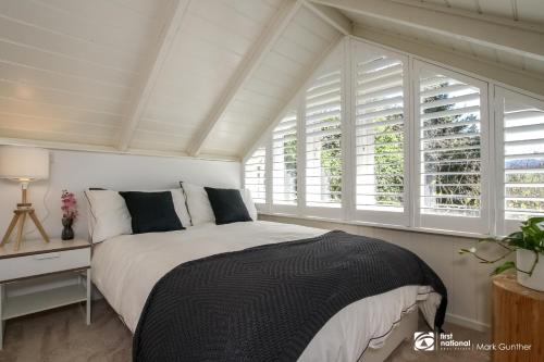 a bedroom with a bed and two windows at Alsace - Healesville in Healesville