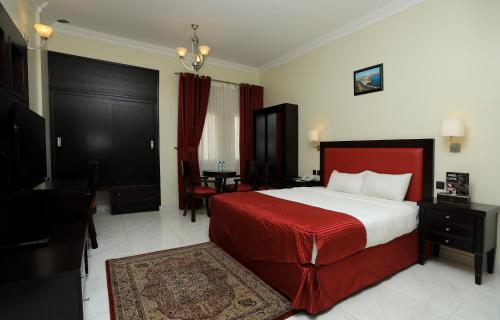 Schlafzimmer mit einem Bett mit einer roten Decke und einem Tisch in der Unterkunft Remas Hotel Suites - Al Khoudh, Seeb, Muscat in Seeb