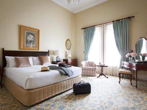 a bedroom with a bed and a table and a piano at The Hotel Windsor in Melbourne