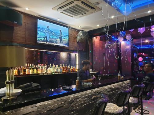 two men sitting at a bar with a tv on the wall at Secrets - Pattaya in Pattaya