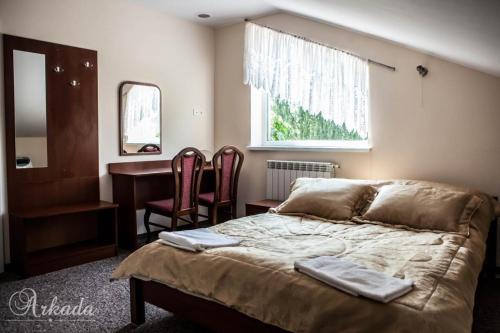 a bedroom with a bed and a desk and a window at Hotel Arkada in Rawa Mazowiecka