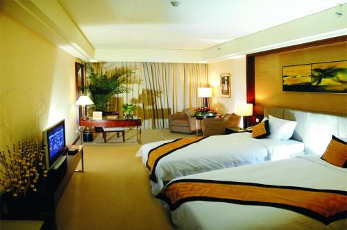 a hotel room with two beds and a living room at Dongguan Richwood Garden Hotel in Dongguan