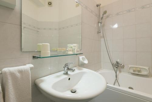 a white bathroom with a sink and a shower at Hotel Airone in Rimini