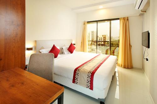 a bedroom with a bed and a table and a window at Mumbai House Luxury Apartments Santacruz East, Mumbai in Mumbai