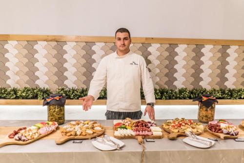 a man standing in front of a table of food at Aqvatonic Hotel - Steaua de Mare in Eforie Nord