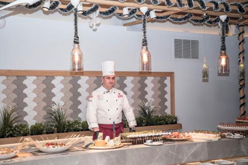 a chef standing in front of a buffet of food at Aqvatonic Hotel - Steaua de Mare in Eforie Nord