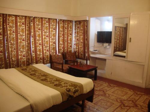 a hotel room with a bed and a chair and a television at Hotel Hamers International in Mussoorie