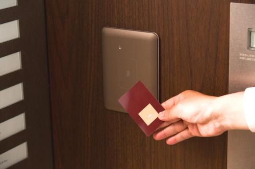a person holding a piece of paper in a door at Hotel Arc Riche Toyohashi in Toyohashi