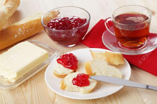 une assiette de pain avec de la confiture et du beurre et une tasse de thé dans l'établissement Chalet Beausoleil 4 étoiles - jacuzzi - au pied des pistes - domaine les sybelles, à Saint-Sorlin-dʼArves