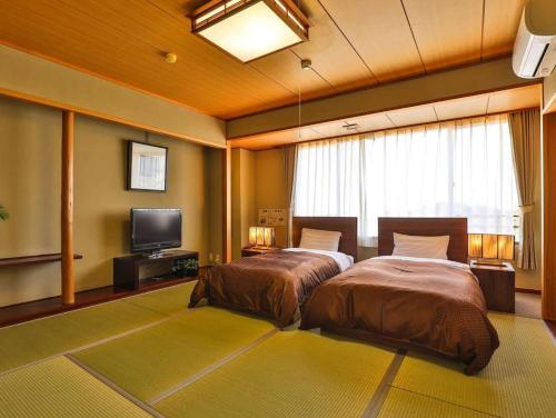 a bedroom with two beds and a flat screen tv at Grampus Sea in Shirahama