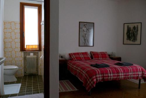 een slaapkamer met een bed met rode kussens en een raam bij Biss Badaliss - Bed & Breakfast in Valdobbiadene