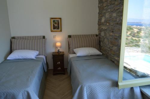 two beds in a room with a window at Villa Rokanes Glass Stone with Pool in Kouvéllai