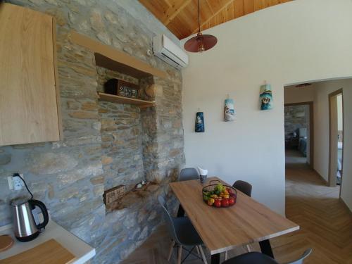 a kitchen with a wooden table and a stone wall at Villa Rokanes Glass Stone with Pool in Kouvéllai