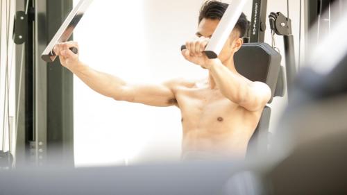 a shirtless man talking on a cell phone in front of a mirror at GTV Hotel in Cikarang