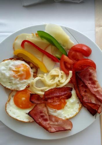 a plate of breakfast food with eggs bacon and tomatoes at Business Hotel Astrum Laus in Levice