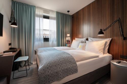 a bedroom with a bed and a desk and a window at PIERDREI Hotel HafenCity Hamburg in Hamburg