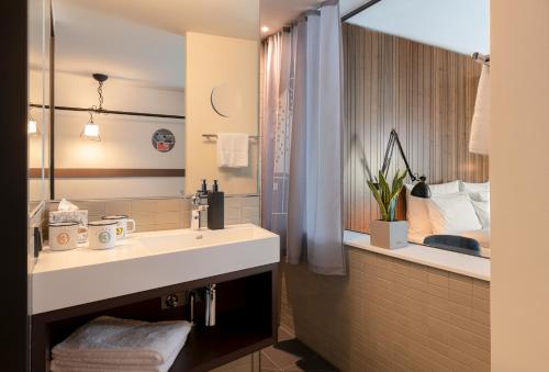 a bathroom with a sink and a large mirror at PIERDREI Hotel HafenCity Hamburg in Hamburg