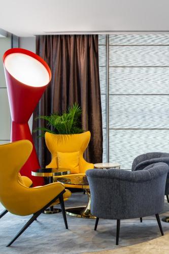 a living room with yellow chairs and a red lamp at Mercure Dubai Barsha Heights Hotel Suites And Apartments in Dubai