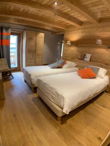 deux lits dans une chambre avec plafonds en bois dans l'établissement Le Gabion, luxueux appartement avec sauna, Serre chevalier Vallée, à Saint-Chaffrey