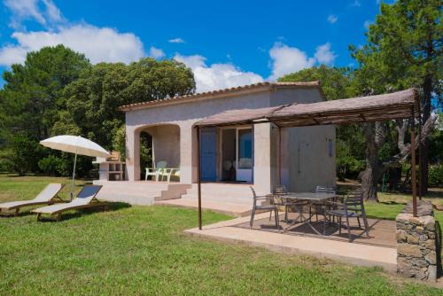 a house with a table and chairs and an umbrella at Domaine de Pianiccia in Sari Solenzara