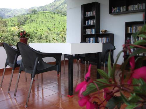 a white table and chairs in a room with a view at Gruenberg Tea Plantation Haus in Munnar
