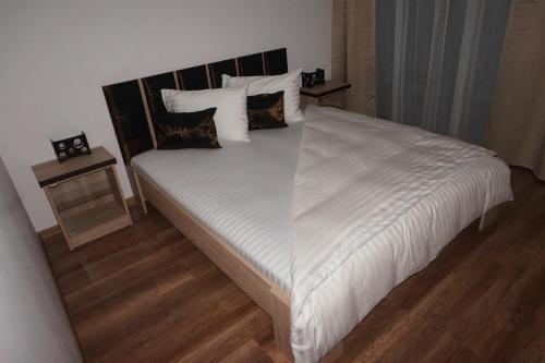 a bedroom with a bed with white sheets and pillows at Citadella Apartament in Târgu-Mureş