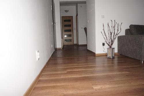 an empty living room with a couch and wooden floors at Citadella Apartament in Târgu-Mureş