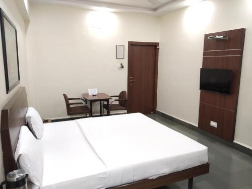 a hotel room with a bed and a table at Hotel Hospice in Surat