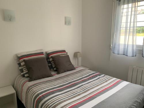 a bedroom with a bed with a striped blanket at Appartement des Tilleuls RDC in Royan