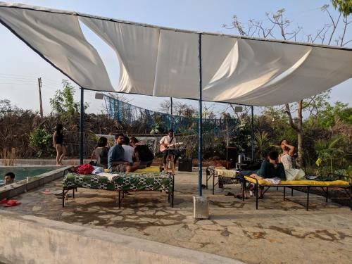 a group of people sitting under a tent next to a pool at Bohemyan Blue Stay in Alibaug
