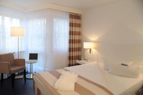 a hotel room with a bed and a chair at relexa hotel Schatten Stuttgart in Stuttgart