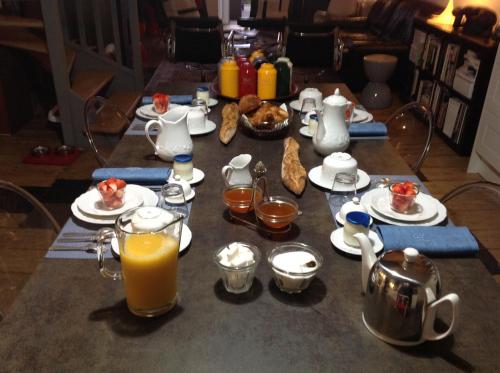 a table topped with plates of food and orange juice at Les Chambres de L'Horloge in Lectoure