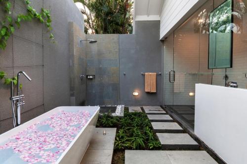La salle de bains est pourvue d'une baignoire avec des fleurs roses. dans l'établissement Villa Coco Bali, à Seminyak